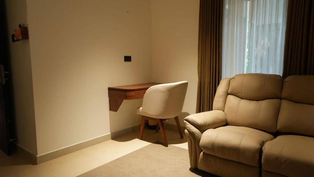 Mizuki Homestay في تريشور: غرفة بها مكتب وكرسي وأريكة