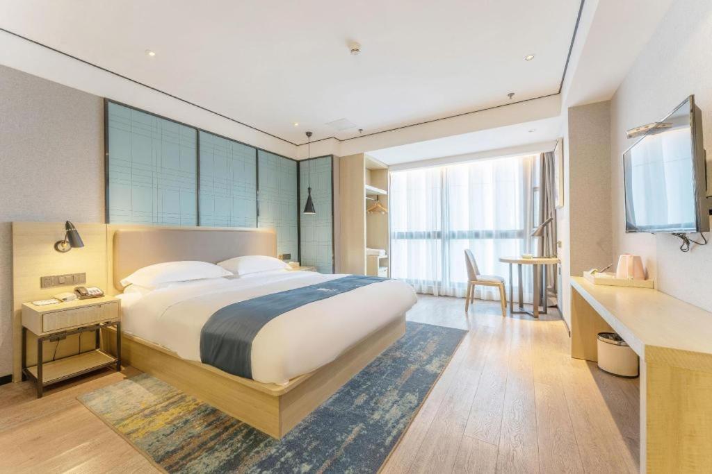 a bedroom with a large bed with a desk and a desk at Echarm Hotel Fuzhou Sanfang Qixiang East Street Metro Station in Fuzhou