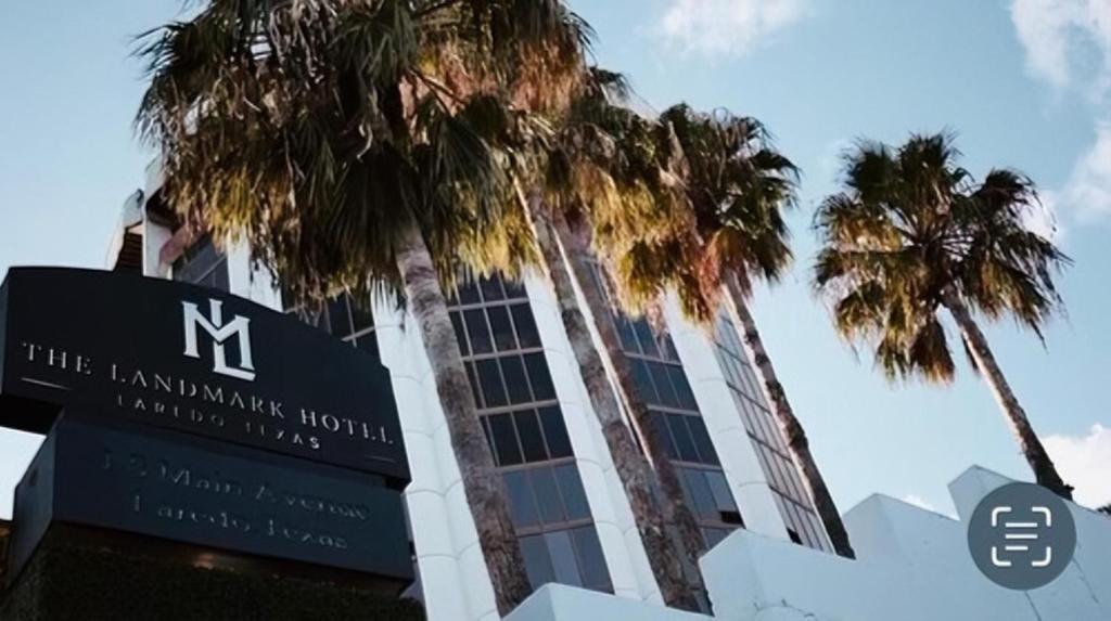 a sign in front of a building with palm trees at The Landmark Hotel in Laredo