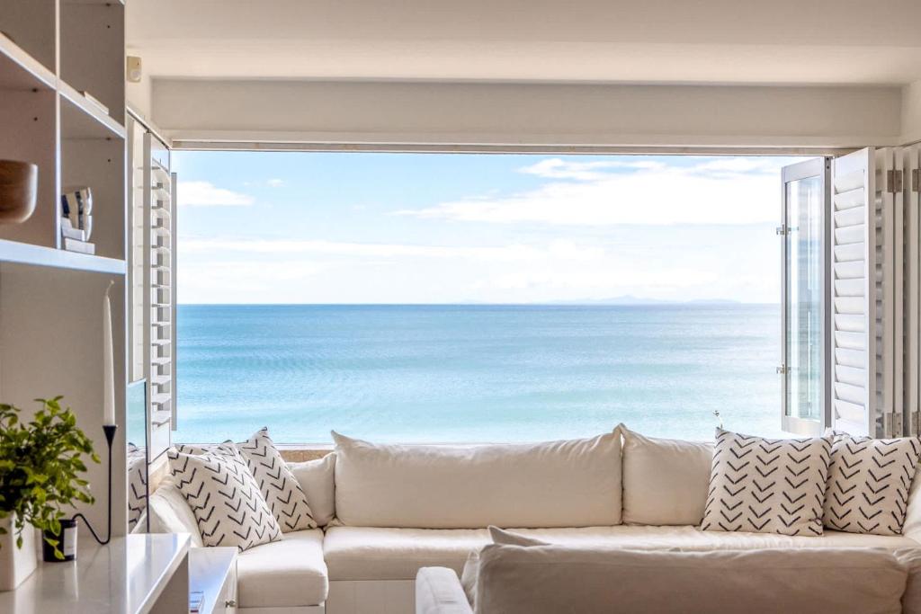 a living room with a white couch and a large window at The Sands Apartment 8 - Stay Waiheke in Waiheke Island