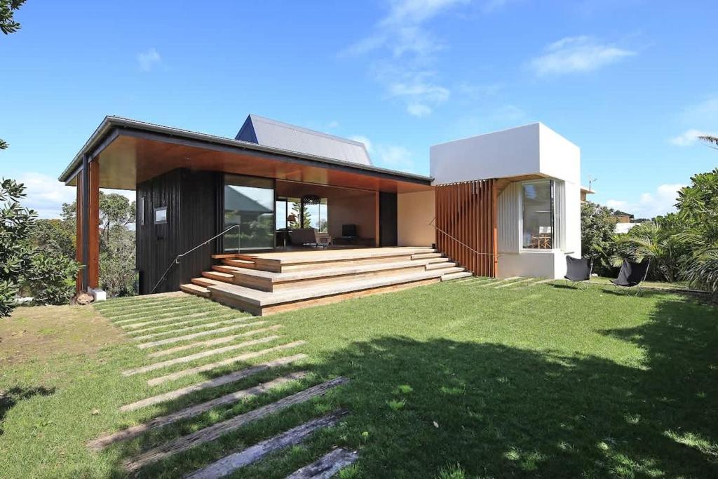 a modern house with a grassy yard in front of it at Number Five - Stay Waiheke in Onetangi