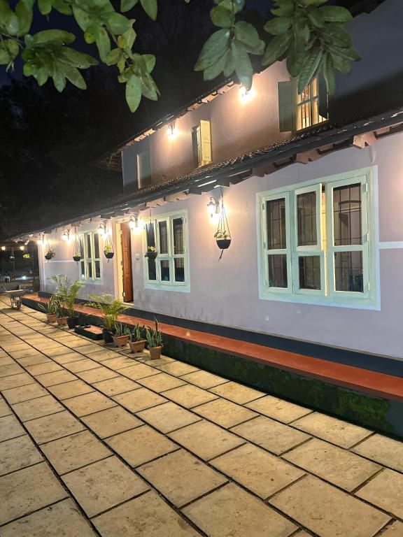 a white house with lights on the side of it at Bucolic Resort in Panamaram
