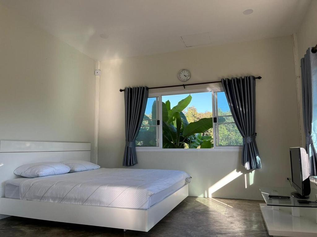 ein weißes Schlafzimmer mit einem Bett und einem Fenster in der Unterkunft Mountain view Villa Private Tropical Garden in Chiang Dao