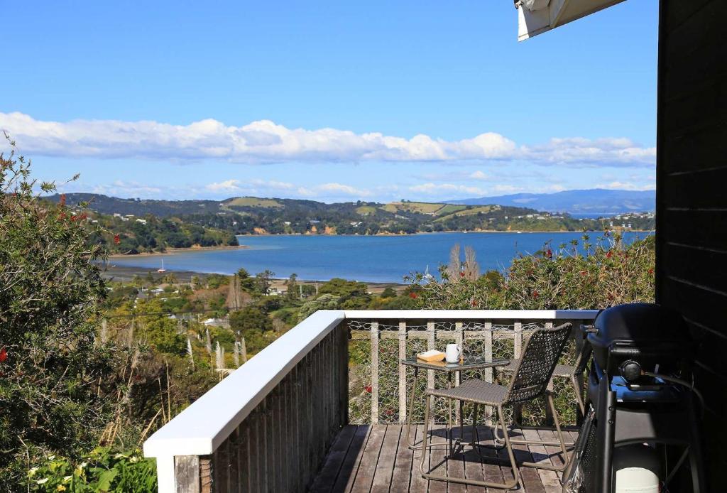 a balcony with a table and a view of a lake at Church Bay Views - Stay Waiheke in Oneroa