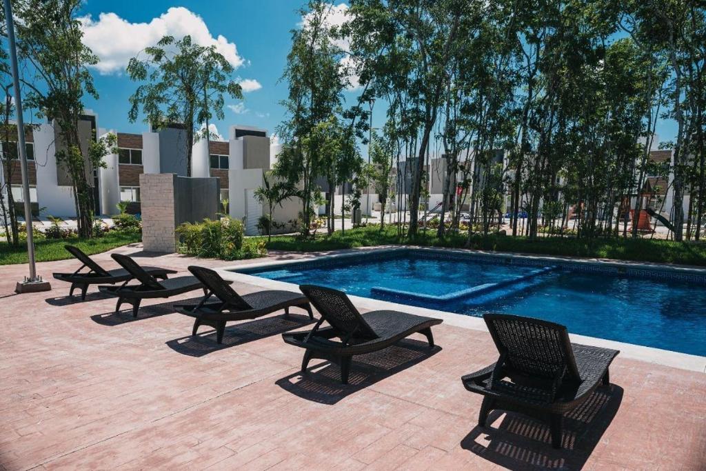 a group of lounge chairs next to a swimming pool at Vacation Home in Playa Del Carmen in Playa del Carmen
