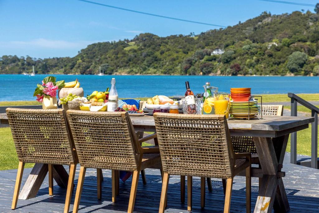 a wooden table with chairs and a table with food on it at Alhambra - Stay Waiheke in Oneroa