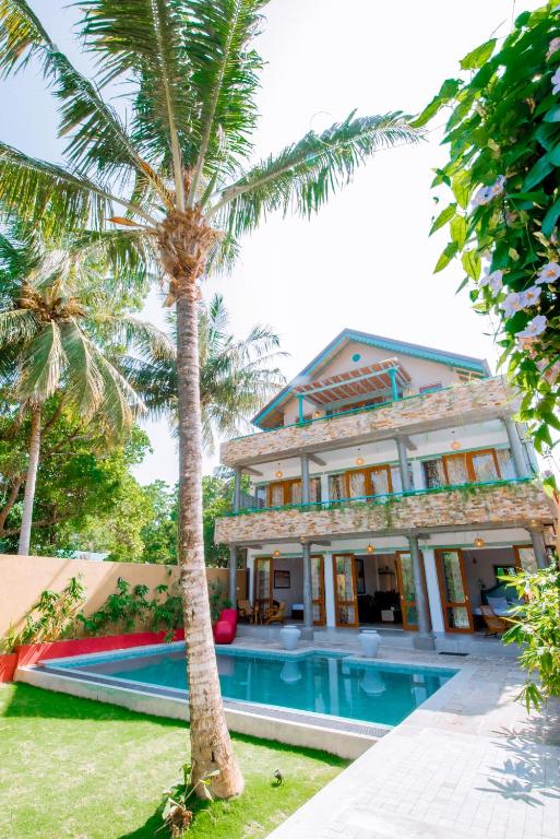 a house with a palm tree and a swimming pool at Sithagi River Front Villa Weligama in Weligama