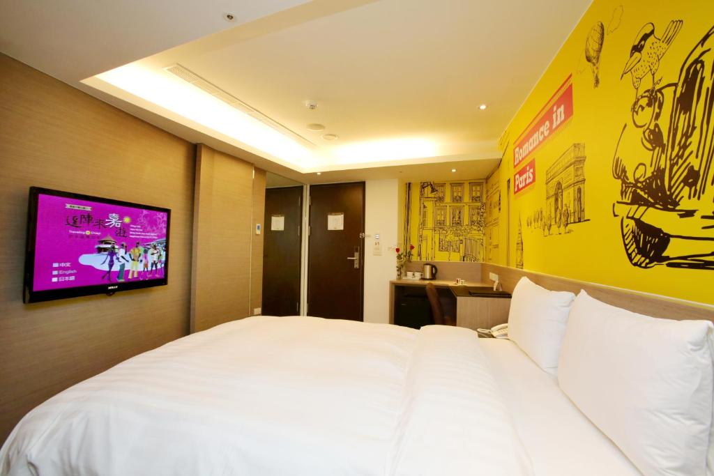 a bedroom with a white bed with a tv on the wall at Chiayi Look Hotel in Chiayi City