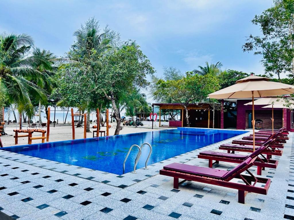 a pool with benches and umbrellas next to a resort at Royal C Resort in Koh Rong Island