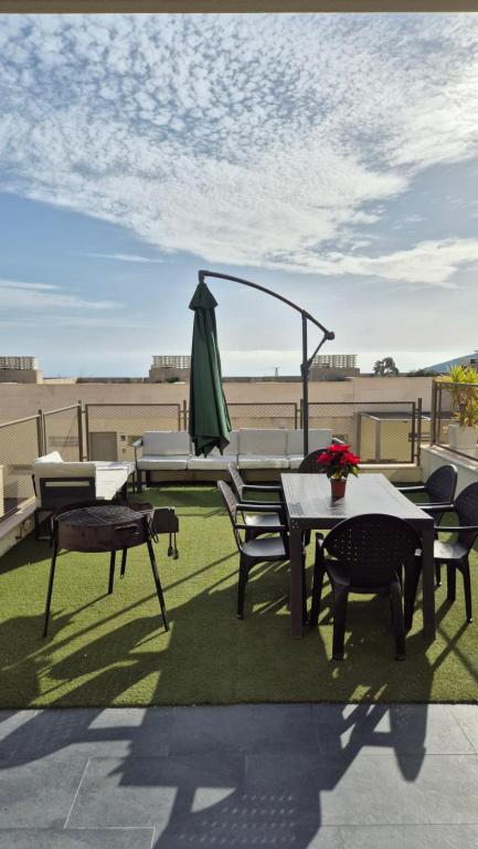 a patio with a table and chairs and an umbrella at Amplio Adosado 160 m, jardín privado barbacoa, vistas al mar, wifi 7 px mascotas in Peñíscola
