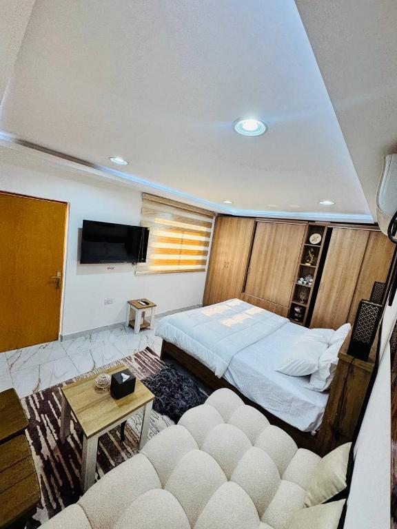 Cozy Private Studio with Garden Al Manhal, Abu Dhabi-5 في أبوظبي: غرفة نوم بها سرير وأريكة وجهاز تلفزيون