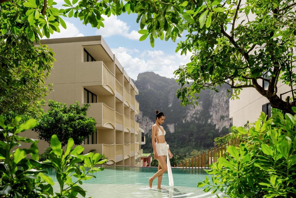 奥南海滩Grand Mercure Krabi Ao Nang的一名女子站在建筑物旁的游泳池里。