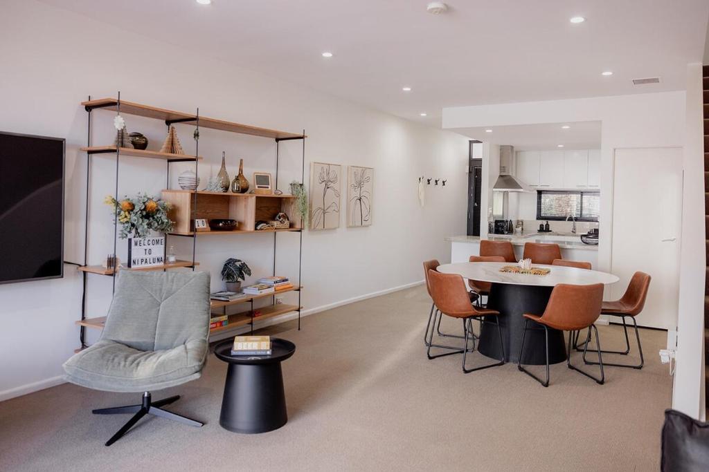 a living room with a table and chairs and a kitchen at Heart of Hobart | CBD Apartment & Parking in Hobart