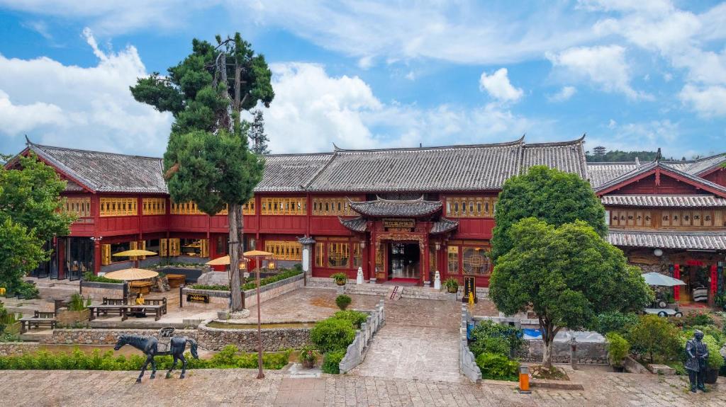Un gran edificio rojo con un caballo delante. en Lijiang Wangfu Hotel, en Lijiang