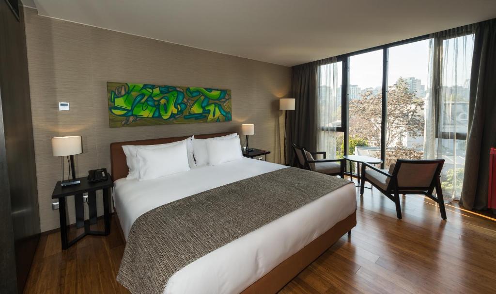 a hotel room with a bed and a large window at Ladera Boutique Hotel in Santiago