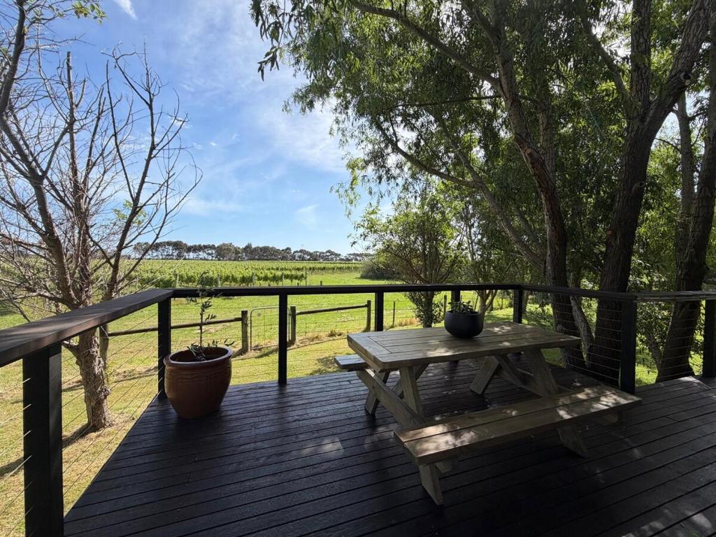 een houten terras met een picknicktafel en uitzicht op een veld bij Vineyard Cottage at Oakdene in Wallington