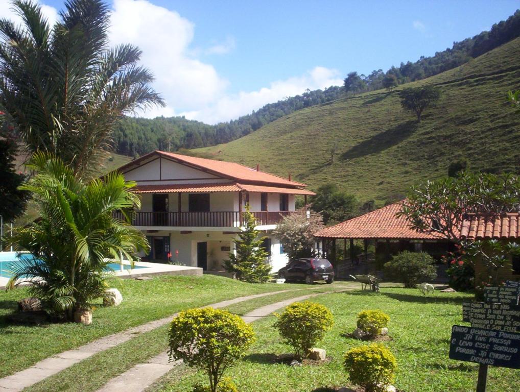 una casa con una palmera frente a una montaña en Fazenda Hotel Alvorada, en Santos Dumont