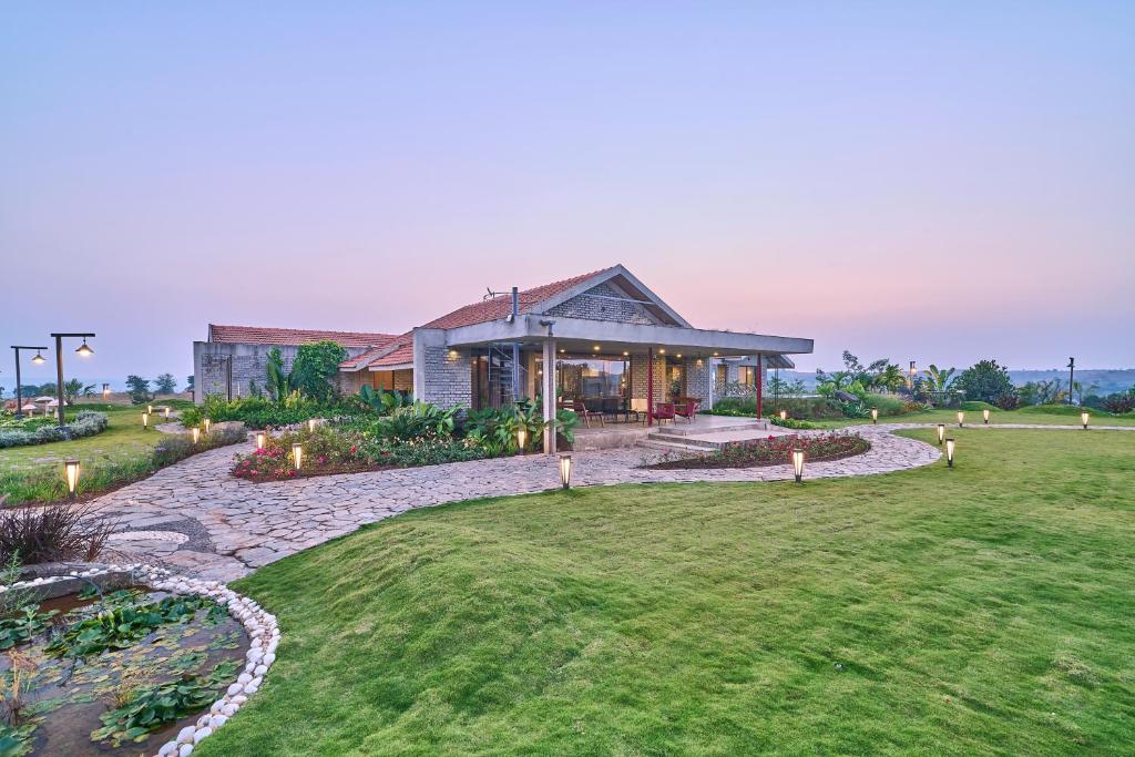 a house with a garden in front of it at SaffronStays Ashfield - 5BHK Eco-Farmhouse with Pools, Jacuzzi, Lawn & Games Room in Nashik