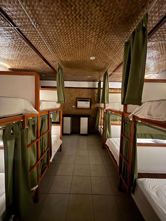 a room with three bunk beds and a tiled floor at Jungle Hostel in Puerto Princesa City