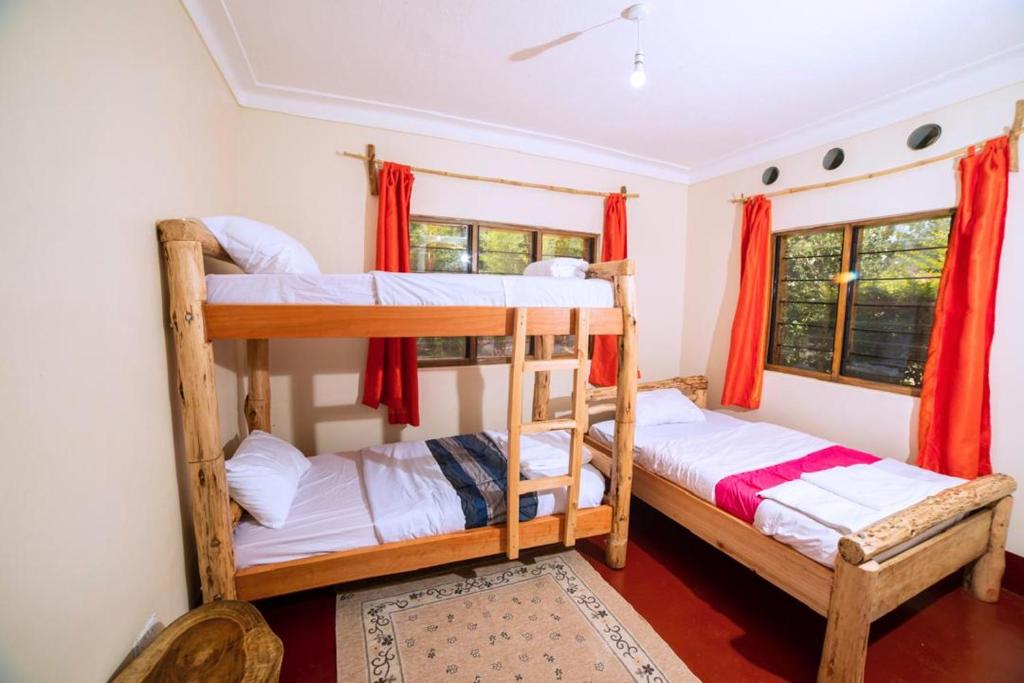 Dos literas en una habitación con cortinas rojas. en Teryet Safari Lodge, en Kapchorwa