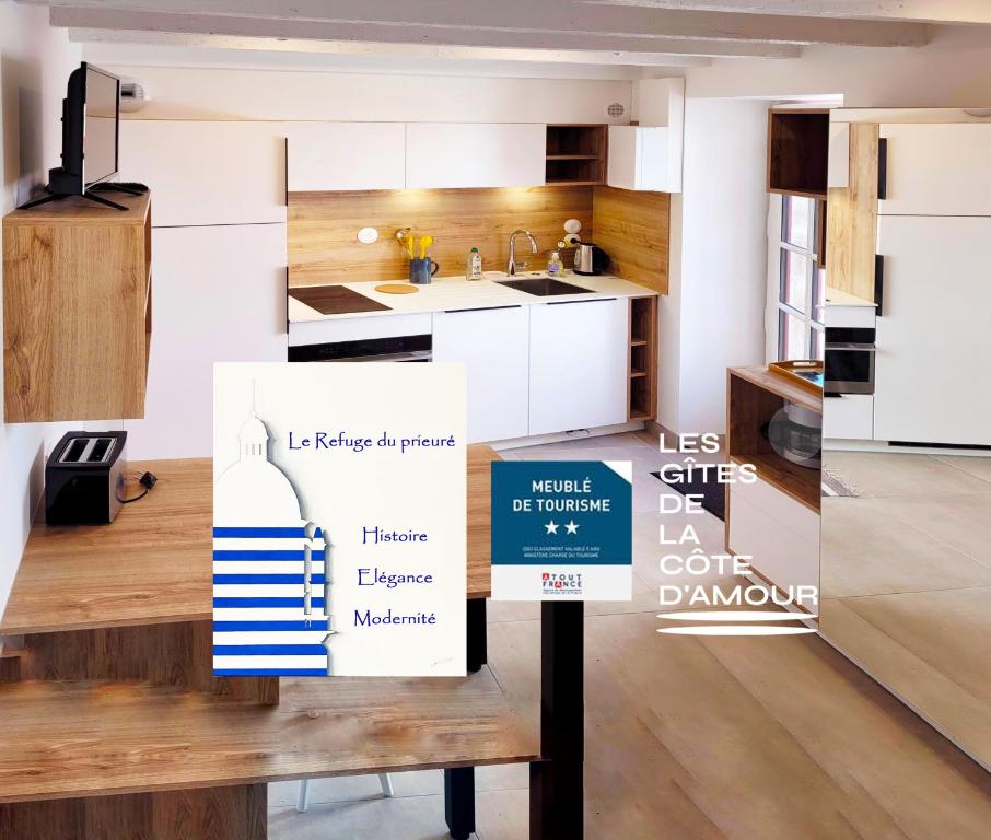 a kitchen with white cabinets and a sign that says less cities la onezone at Le refuge du prieuré - Les Gîtes de la Côte d'Amour in Batz-sur-Mer