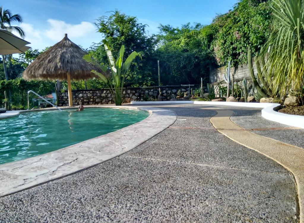 una piscina con sombrilla junto a un complejo en Casa Del Sol en Lo de Marcos