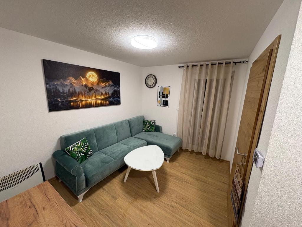Una sala de estar con un sofá verde y una mesa. en SkyLux Vlašić, en Šišava