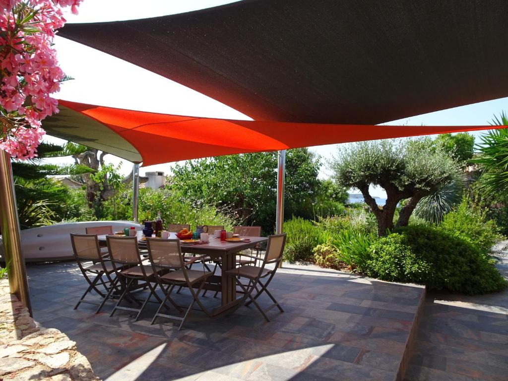 a table and chairs under an umbrella on a patio at Les Voiles in Pinarellu