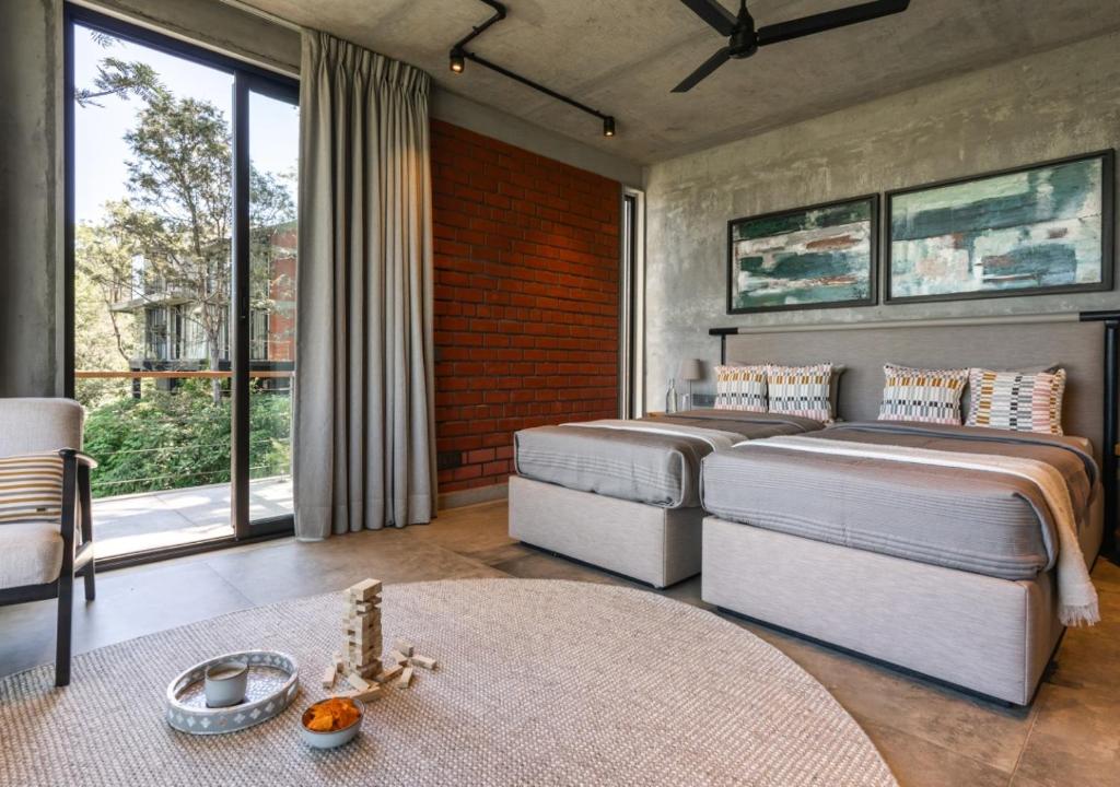 2 Betten in einem Schlafzimmer mit einem großen Fenster in der Unterkunft LohonoStays Amani Villa 9B in Coonoor