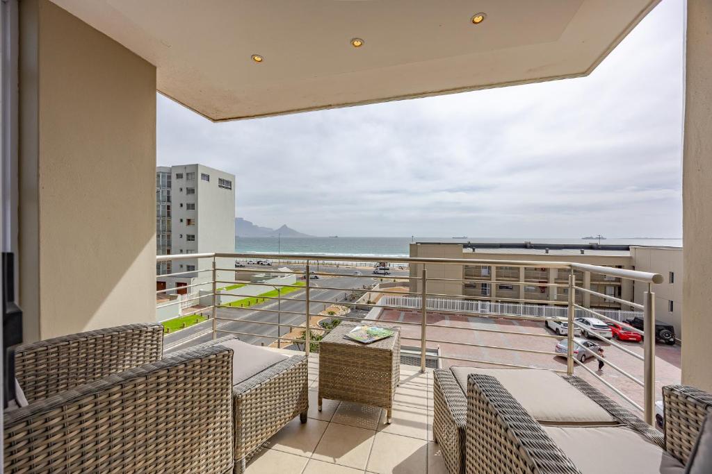 a balcony with chairs and a view of the ocean at Luxury Ocean View Beachfront 2 bed apartment -206 The Waves, Blouberg, Cape Town in Bloubergstrand