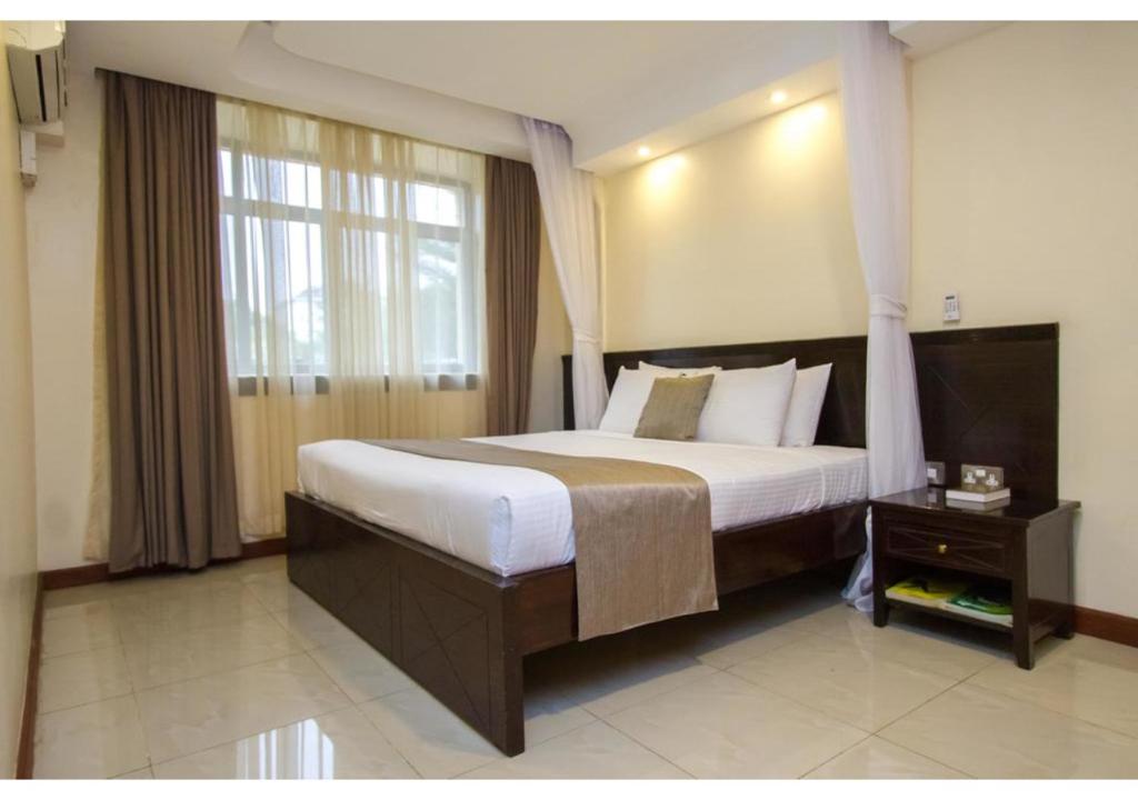 a bedroom with a large bed and a window at The Pinecone Hotel Kisumu in Kisumu