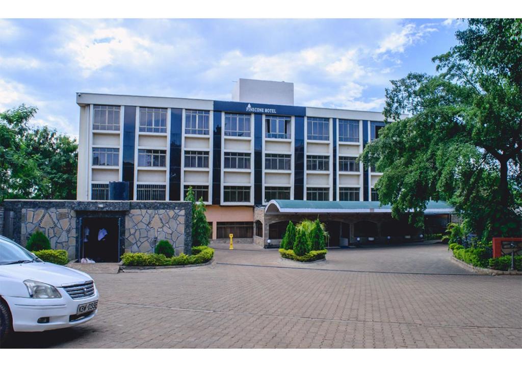 Un gran edificio con un coche aparcado delante. en The Pinecone Hotel Kisumu, en Kisumu
