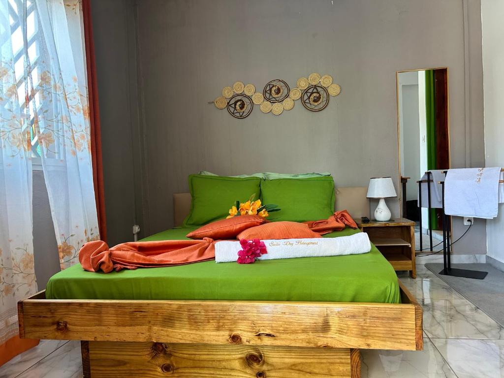 PamandziにあるSteilaDay Hébergement 976の緑のシーツとオレンジ色の枕が置かれたベッド