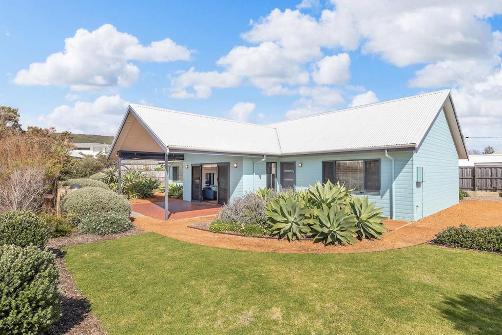 ein blaues Haus mit einem weißen Dach in einem Hof in der Unterkunft Beachfront Prevelly Exclusive Holiday Home in Prevelly