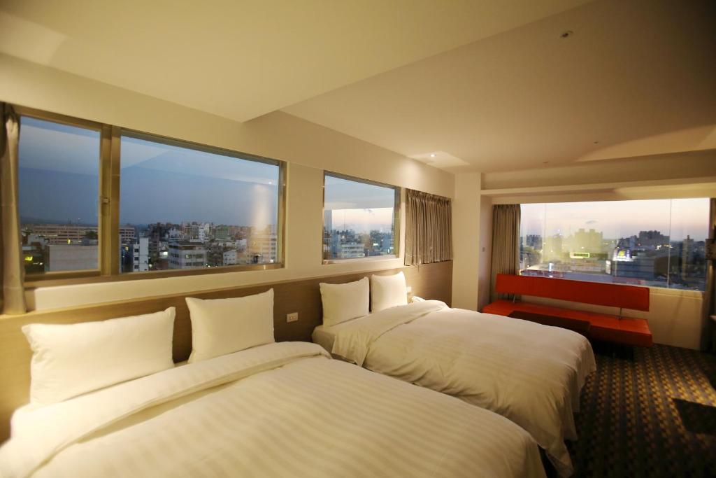 two beds in a hotel room with large windows at Chiayi Look Hotel in Chiayi City