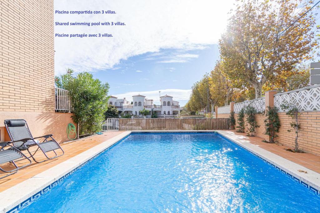 a swimming pool in a yard next to a building at Jouvacations Villa 3 Freser con piscina compartida in Empuriabrava