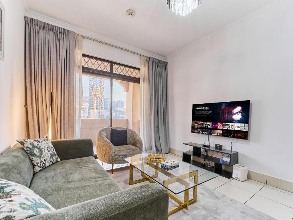 a living room with a couch and a tv at Golden Homes 1BR Reehan miniPalais Beside Burjh & Dubai mall Downtown in Dubai
