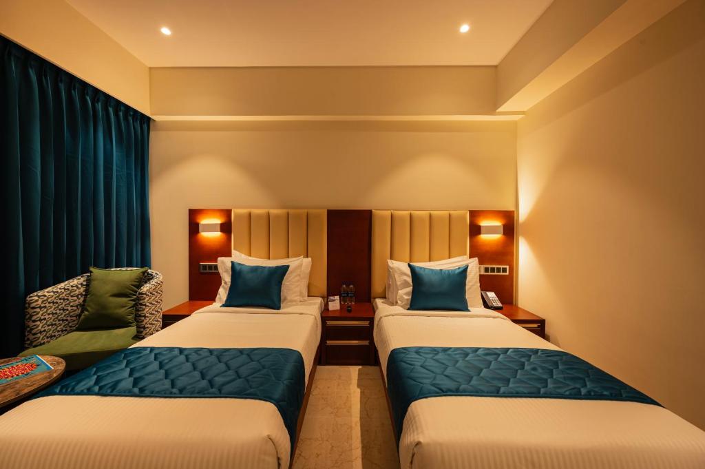 a hotel room with two beds and a couch at Hotel Classic Pavilion in Trivandrum