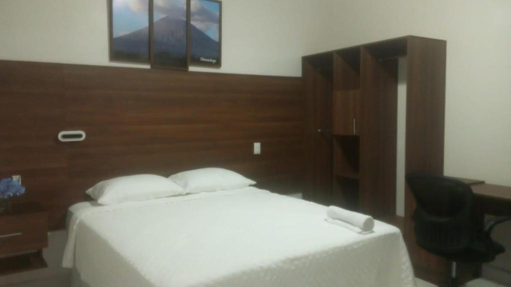 a bedroom with a white bed and a desk at Hostal Boutique Isabel in Managua