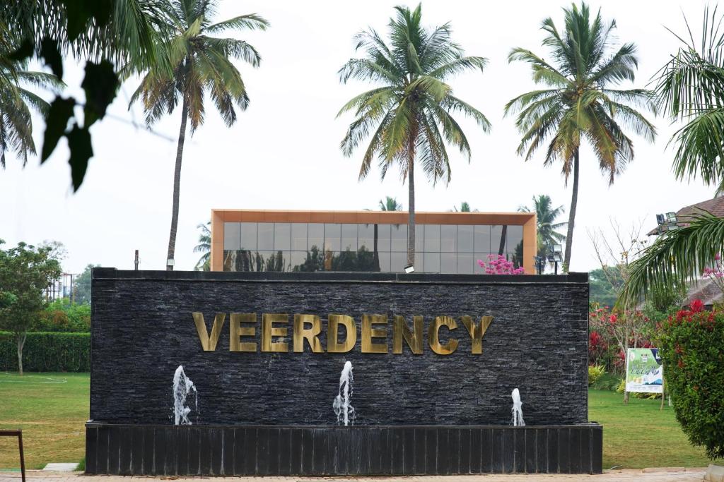 a sign in a park with palm trees in the background at Veerdency Luxury resort in Bengaluru