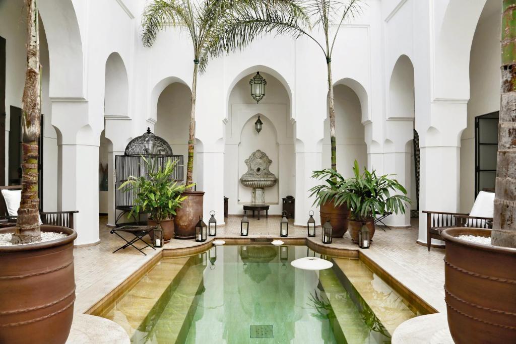 an indoor pool in the middle of a building with palm trees at Dar Mo'Da in Marrakesh