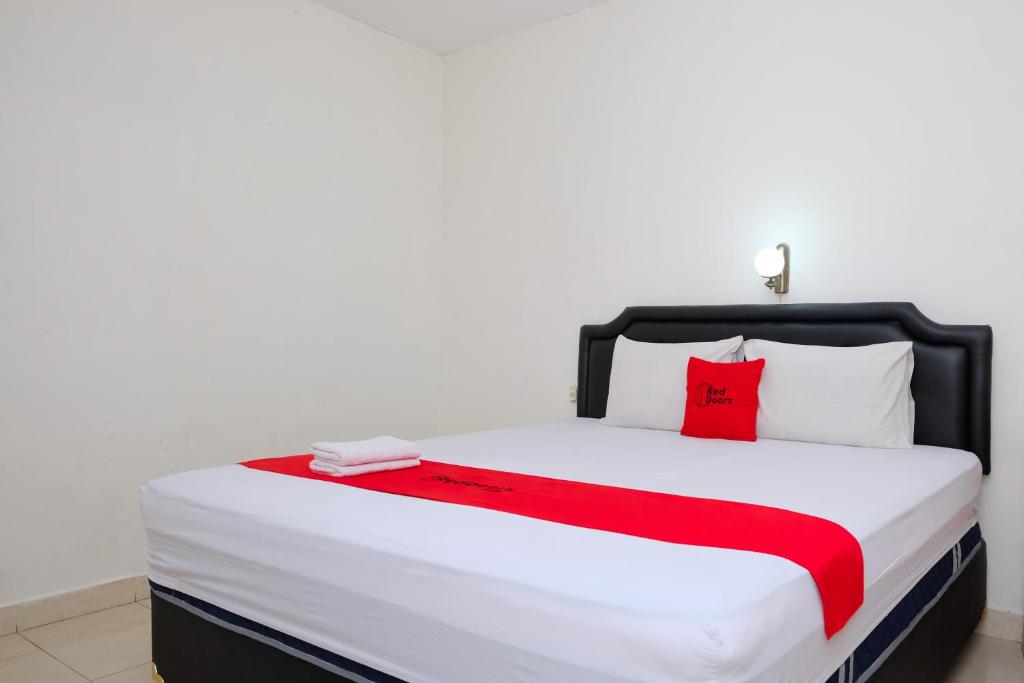 a bedroom with a large bed with a red pillow at RedDoorz at Hotel Raditia Graha Yogyakarta in Yogyakarta