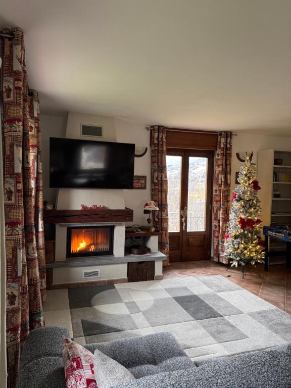 a living room with a fireplace and a christmas tree at HabitAlp360 in Roisan