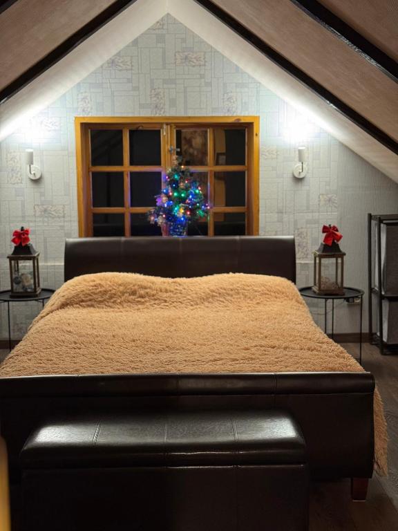 a bedroom with a bed and a christmas tree in a window at Guest house ''Stropiki'' with Sauna and hot Tub in Daugavpils