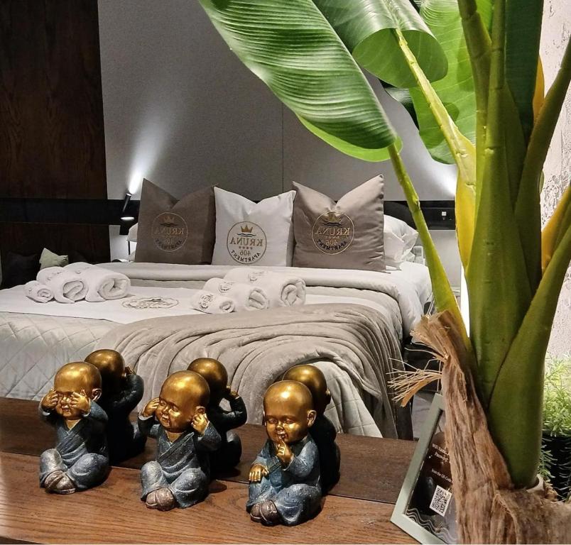 three little monk statues in front of a bed at KRUNA 406 Apartment in Becici