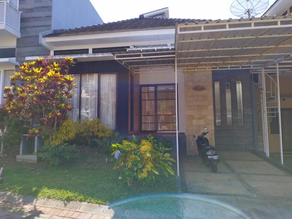 a house with a motorcycle parked in front of it at Villa Kusuma Pinus M10 in Batu