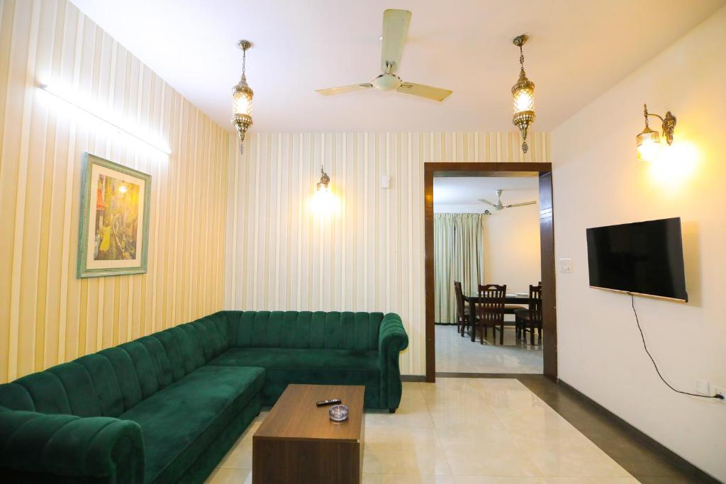 a living room with a green couch and a television at Nestoa Suites - Benson Town in Bangalore