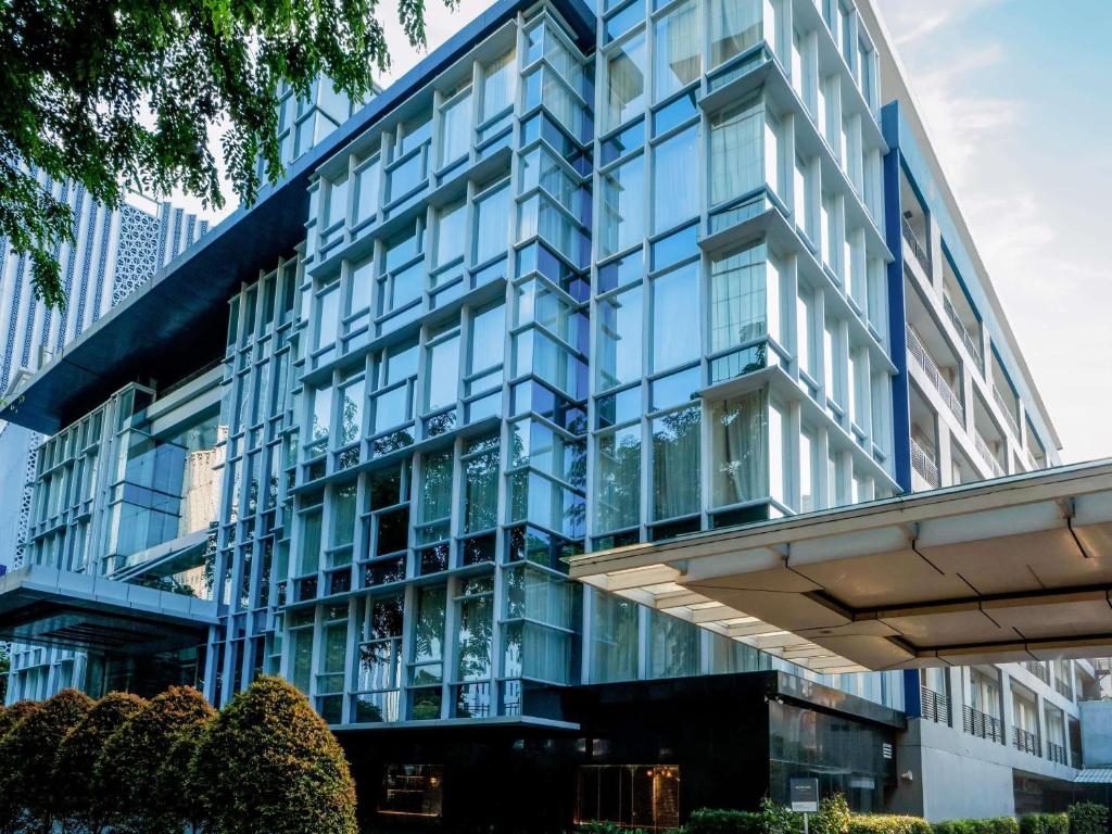 Un edificio azul con ventanas de vidrio en una ciudad. en Mercure Jakarta Sabang, en Yakarta
