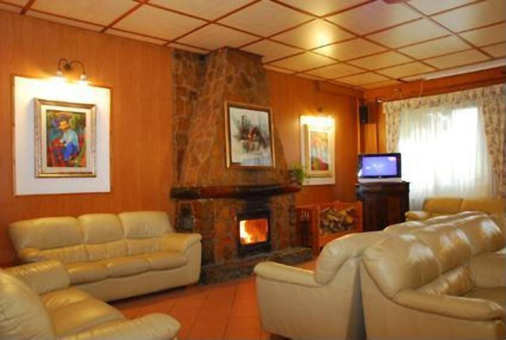 a living room with white furniture and a fireplace at Hotel Bamby in Pescasseroli