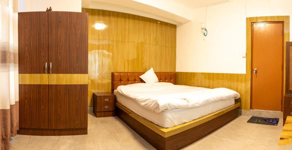 Un dormitorio con una cama y una pared de madera. en Hotel Sonam, en Dhulikhel